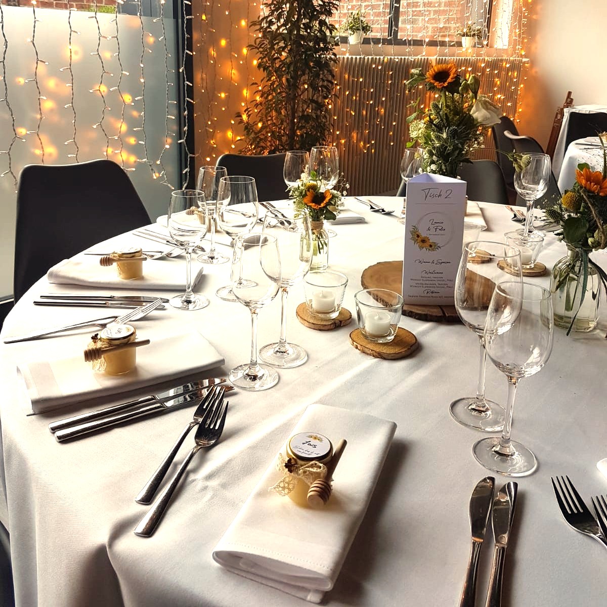 Honigglas-Etikett-Hochzeit Dekorierter Hochzeits-Tisch mit Honiggläsern auf deren Deckel ein Etikett mit dem Gastnamen klebt